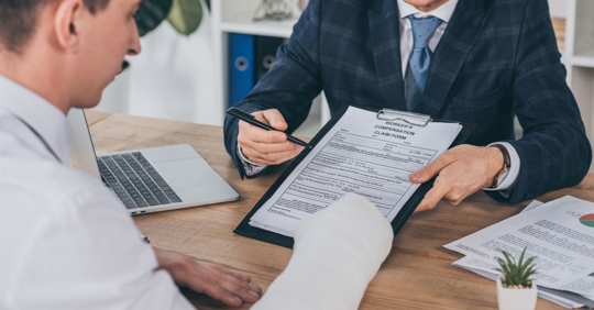 man with broken arm looking over forms with workers' comp. attorney
